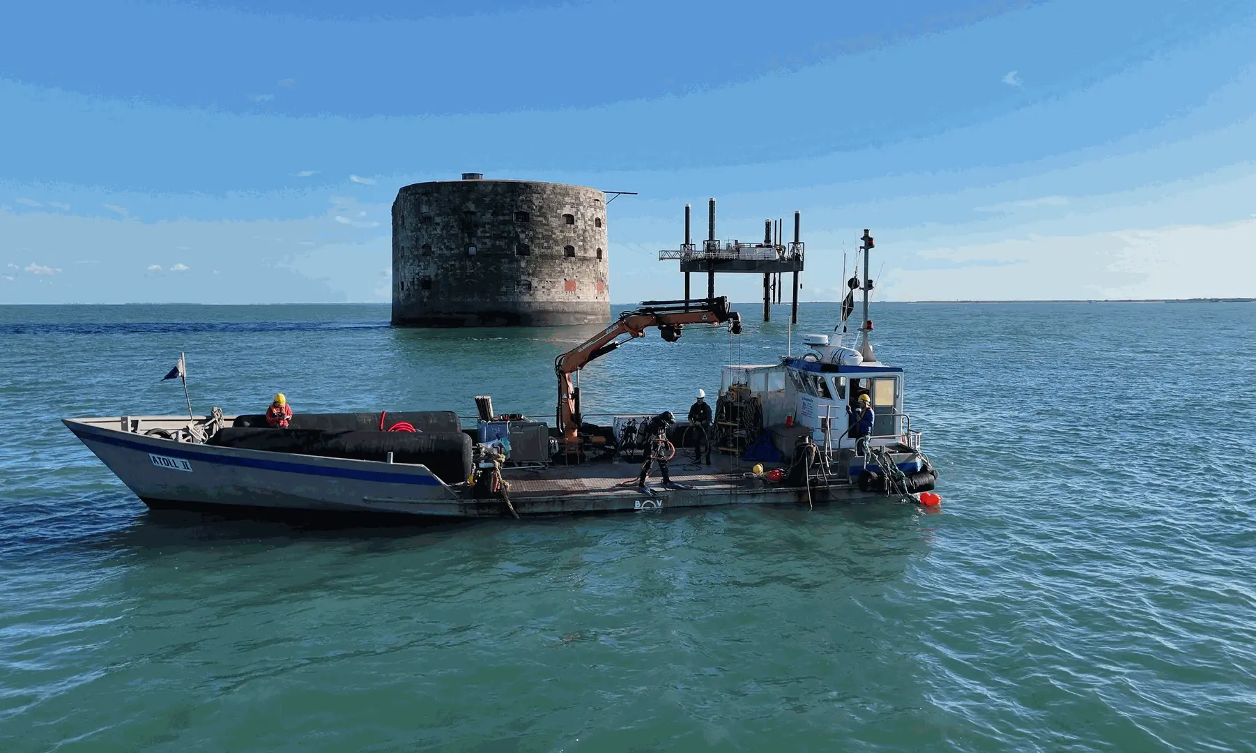 A workboat with a crane and a diver on the deck